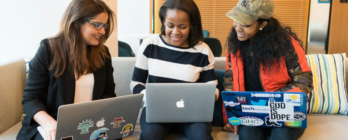 three women sitting on sofa with MacBook