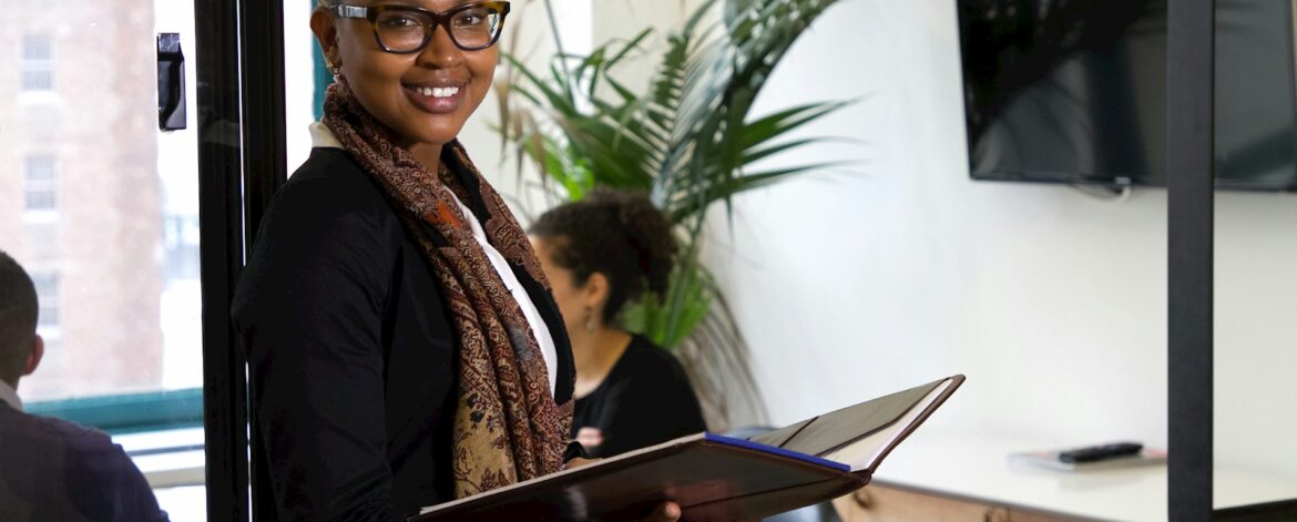 a woman standing in an office holding a binder