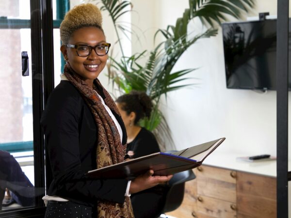 a woman standing in an office holding a binder